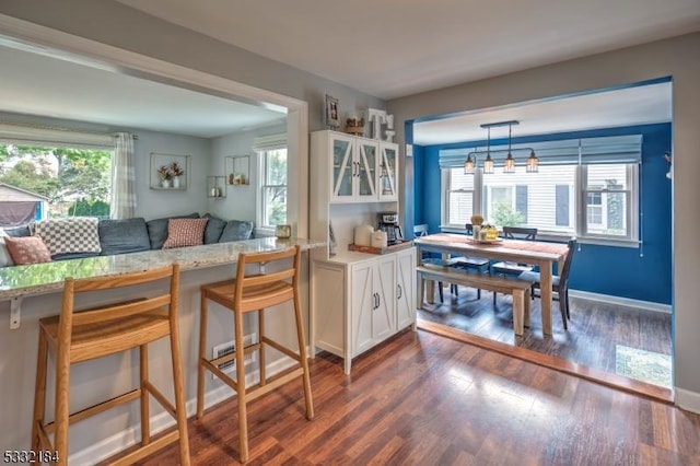 kitchen with kitchen peninsula, white cabinets, a kitchen breakfast bar, and plenty of natural light