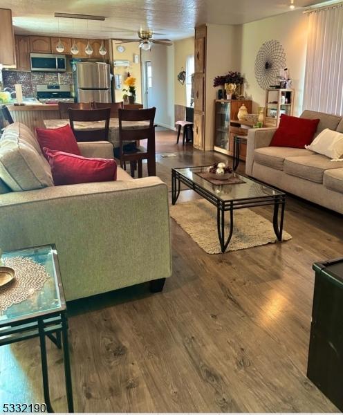 living room with ceiling fan and dark wood-type flooring