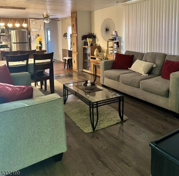 living room with ceiling fan and dark wood-type flooring