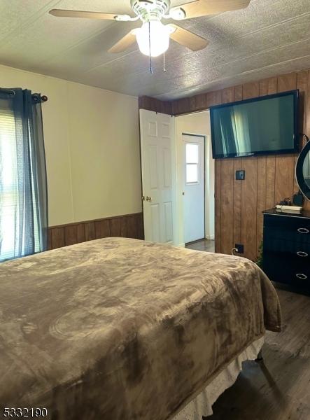 bedroom featuring ceiling fan and wooden walls