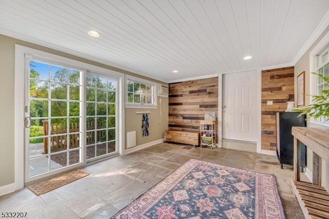 doorway with crown molding, wooden walls, and wood ceiling