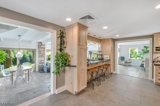 kitchen with beamed ceiling, pendant lighting, and light brown cabinetry