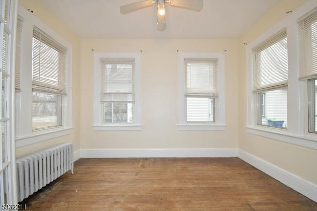 unfurnished room featuring ceiling fan, plenty of natural light, radiator heating unit, and hardwood / wood-style flooring