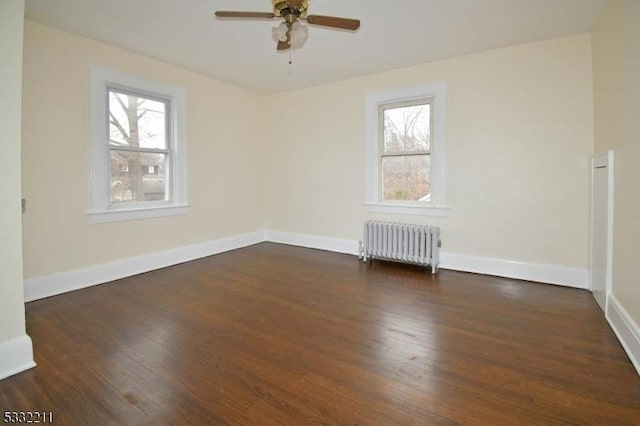 spare room with ceiling fan, dark wood-type flooring, and radiator