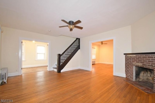 unfurnished living room with light hardwood / wood-style floors, ceiling fan, and a fireplace