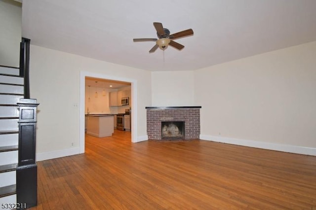 unfurnished living room with ceiling fan, wood-type flooring, and a fireplace