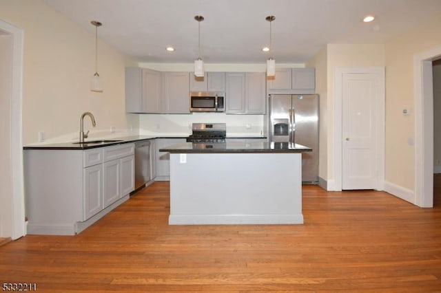 kitchen with gray cabinets, stainless steel appliances, light wood-type flooring, pendant lighting, and sink