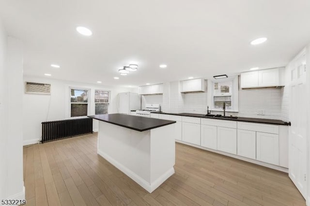 kitchen featuring light hardwood / wood-style floors, tasteful backsplash, white appliances, white cabinets, and sink