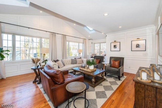 living room with vaulted ceiling with skylight, plenty of natural light, and light hardwood / wood-style flooring