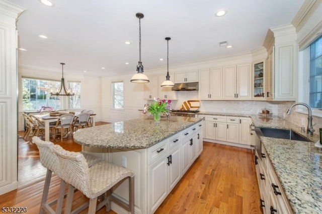 kitchen featuring decorative light fixtures, light stone countertops, white cabinets, and a center island