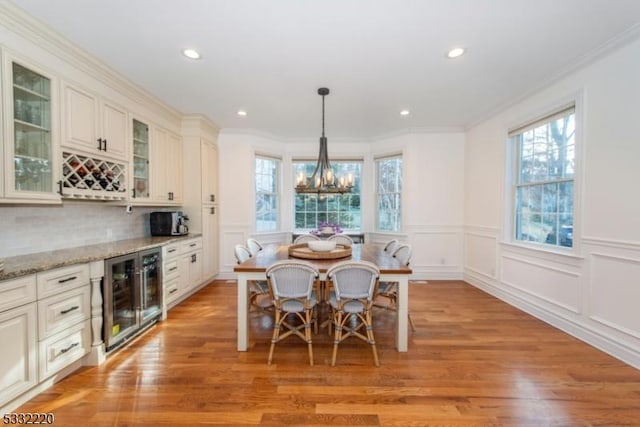 dining room with a wealth of natural light, crown molding, and wine cooler