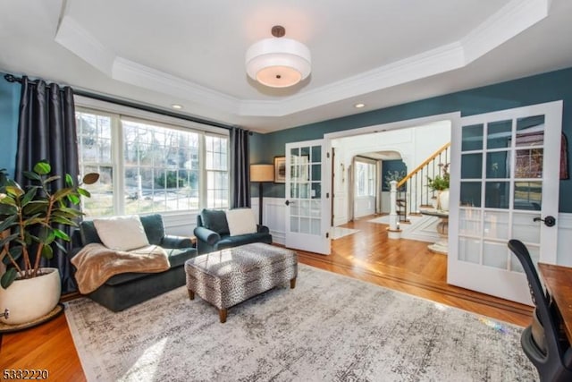 sitting room featuring french doors, wood-type flooring, and a raised ceiling