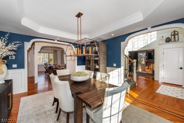 dining area featuring hardwood / wood-style flooring, a tray ceiling, and ornamental molding