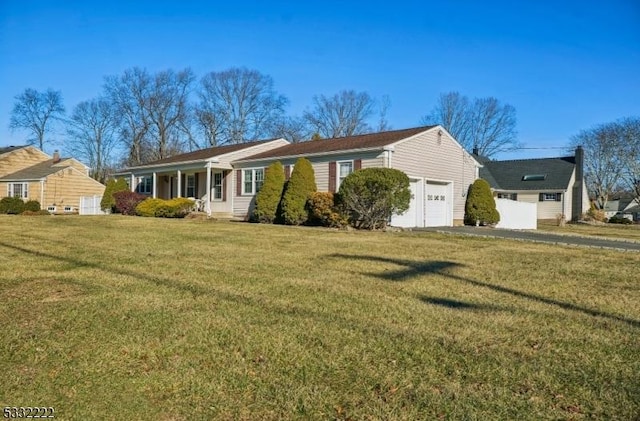 single story home featuring covered porch, a front yard, and a garage