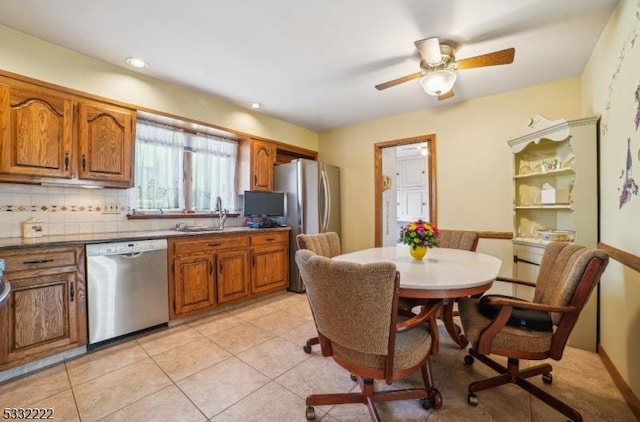 kitchen with stainless steel appliances, sink, ceiling fan, light tile patterned floors, and backsplash