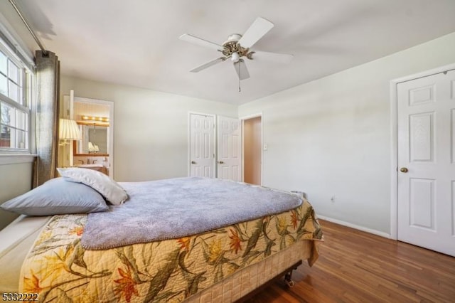 bedroom featuring ensuite bathroom, dark hardwood / wood-style flooring, ceiling fan, and multiple windows