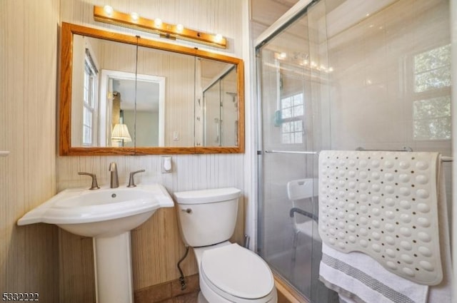 bathroom featuring toilet and a shower with shower door