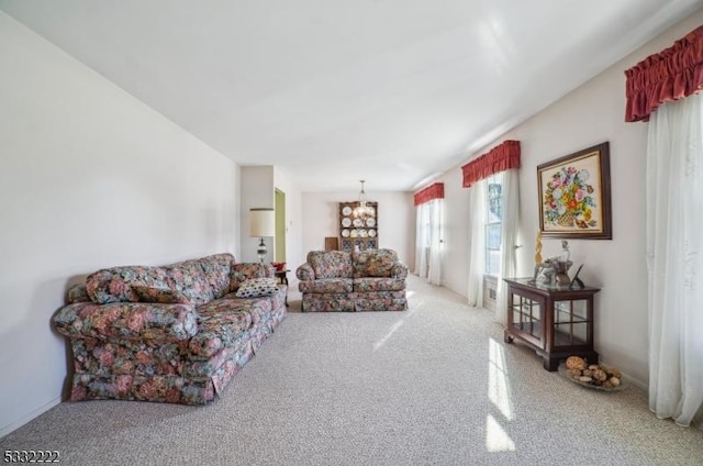 carpeted living room with an inviting chandelier