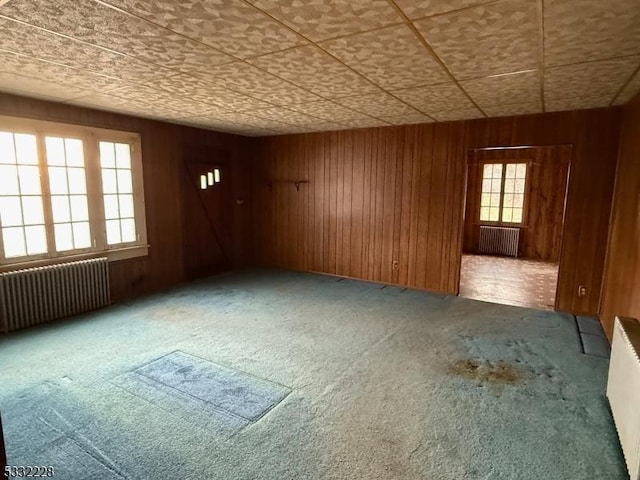 unfurnished room with radiator, wooden walls, and carpet floors