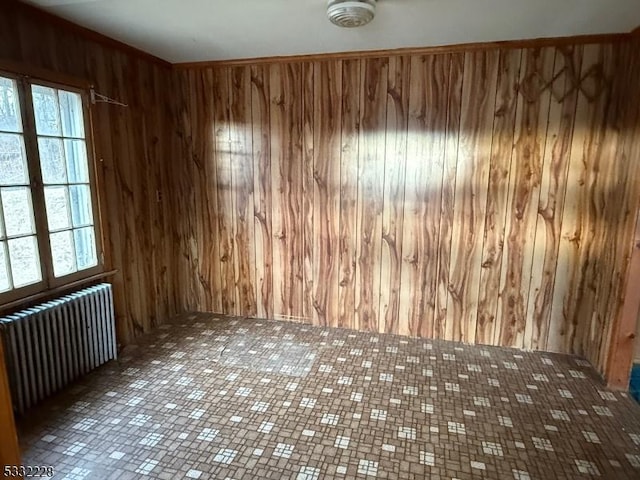 spare room with radiator and wood walls