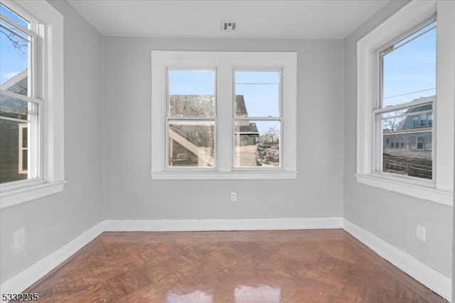 spare room featuring parquet floors and plenty of natural light