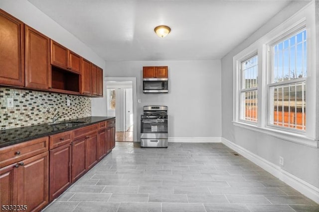 kitchen with stainless steel appliances, dark stone counters, tasteful backsplash, and sink