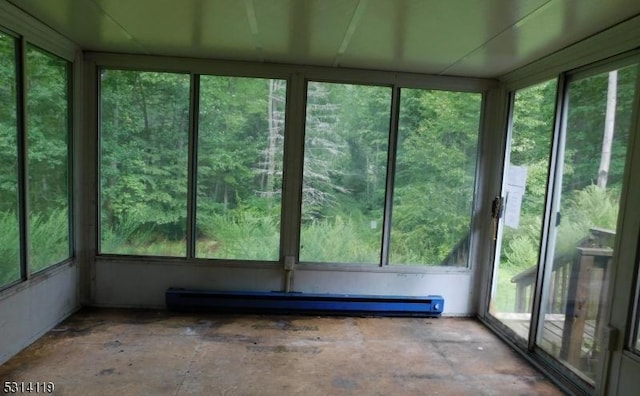 unfurnished sunroom featuring a wealth of natural light and a baseboard heating unit