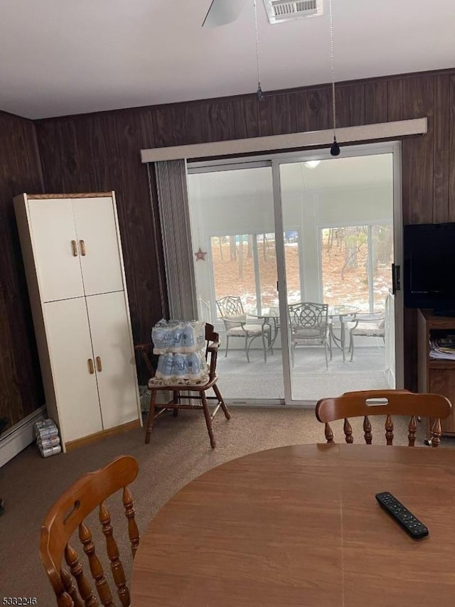 carpeted dining area featuring wood walls