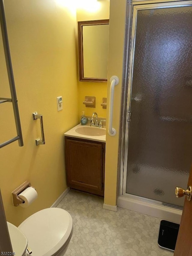 bathroom with a shower with shower door, toilet, and vanity