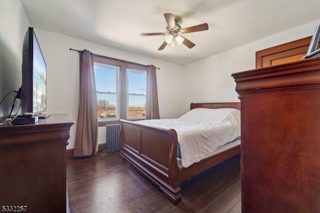 bedroom featuring dark wood-type flooring, radiator heating unit, and ceiling fan