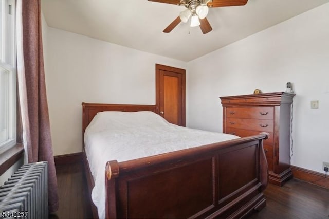 bedroom featuring dark hardwood / wood-style flooring, radiator heating unit, and ceiling fan