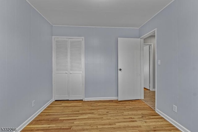 unfurnished bedroom with light hardwood / wood-style flooring, a closet, and crown molding