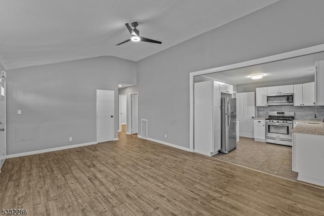 unfurnished living room with ceiling fan, light hardwood / wood-style floors, lofted ceiling, and sink