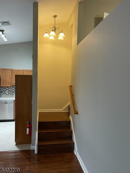 stairway with hardwood / wood-style floors and a notable chandelier