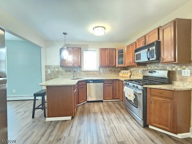 kitchen with kitchen peninsula, a breakfast bar, stainless steel appliances, sink, and hanging light fixtures