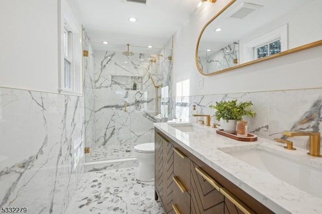 bathroom featuring toilet, vanity, tile walls, and a shower with door