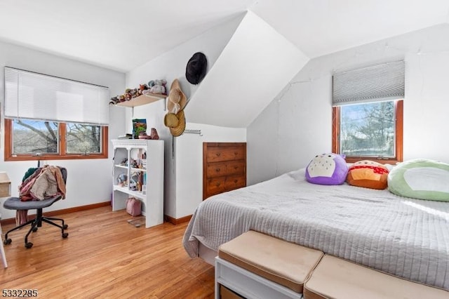 bedroom featuring lofted ceiling, light wood-type flooring, and multiple windows