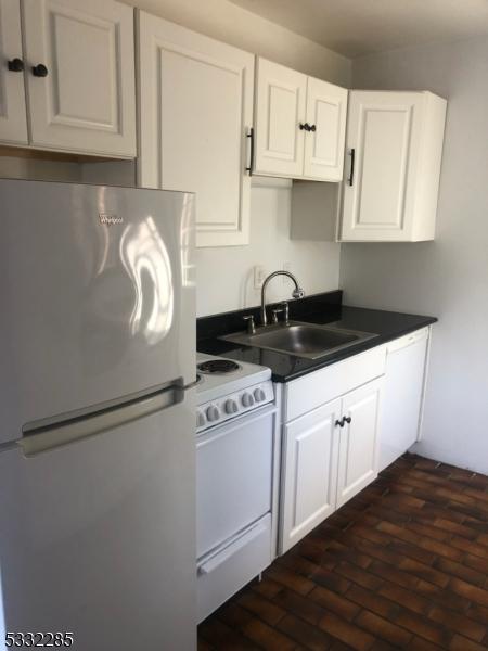 kitchen featuring white cabinets, stainless steel fridge, white stove, and sink