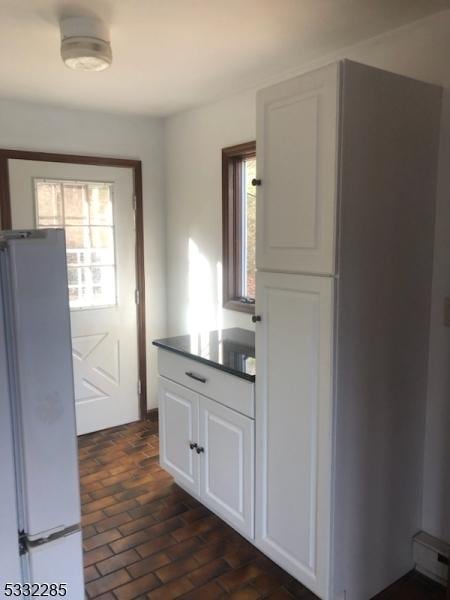 kitchen featuring white cabinets, white fridge, and a wealth of natural light