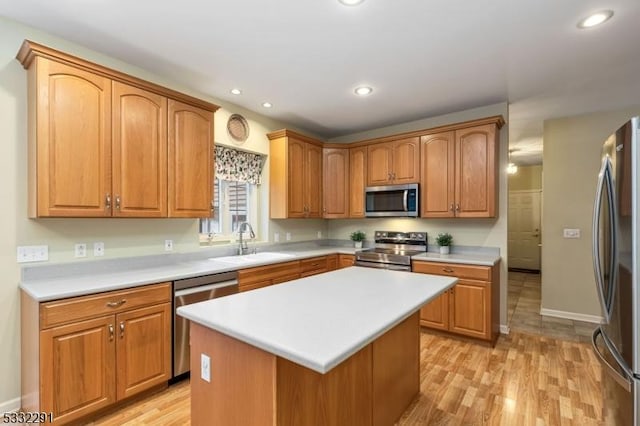 kitchen featuring appliances with stainless steel finishes, light hardwood / wood-style floors, a kitchen island, and sink