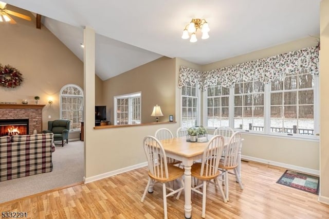 dining space with hardwood / wood-style floors, ceiling fan with notable chandelier, and vaulted ceiling with beams