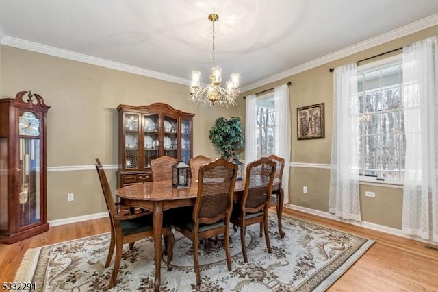 dining space featuring light hardwood / wood-style flooring, an inviting chandelier, and crown molding