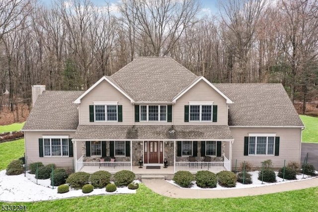 front facade featuring covered porch and a front lawn