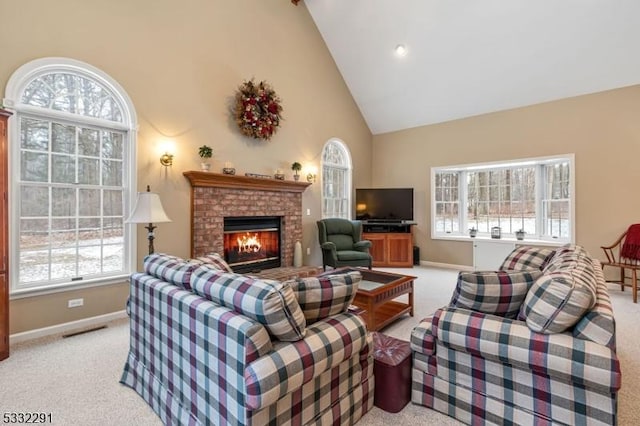 living room with high vaulted ceiling, a brick fireplace, and light carpet