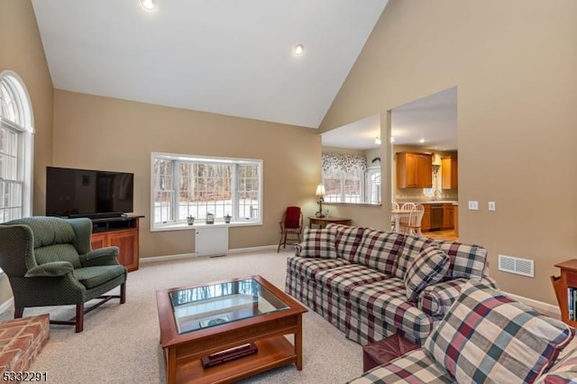 carpeted living room featuring high vaulted ceiling