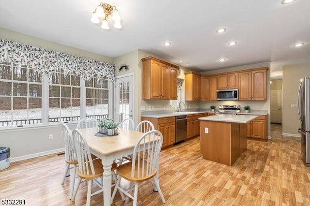 kitchen with appliances with stainless steel finishes, light hardwood / wood-style floors, a center island, a notable chandelier, and sink