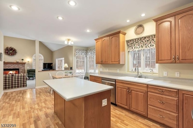 kitchen featuring a brick fireplace, light hardwood / wood-style flooring, dishwasher, and sink