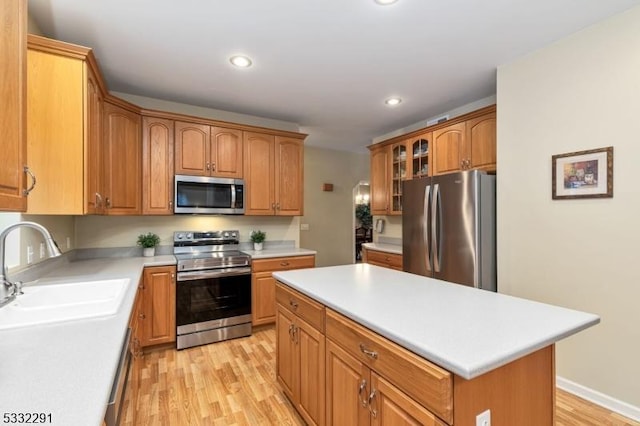 kitchen featuring sink, stainless steel appliances, light hardwood / wood-style floors, and a center island