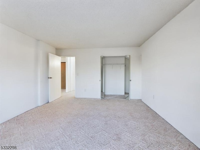 unfurnished bedroom with light colored carpet, a closet, and a textured ceiling