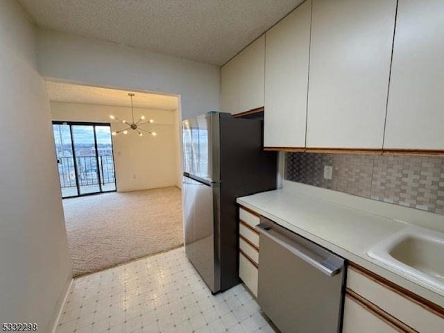 kitchen with light carpet, appliances with stainless steel finishes, a notable chandelier, pendant lighting, and white cabinetry